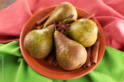 Ripe pears and cinnamon sticks in bowl,