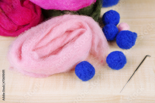 Wool for felting with needle on wooden background