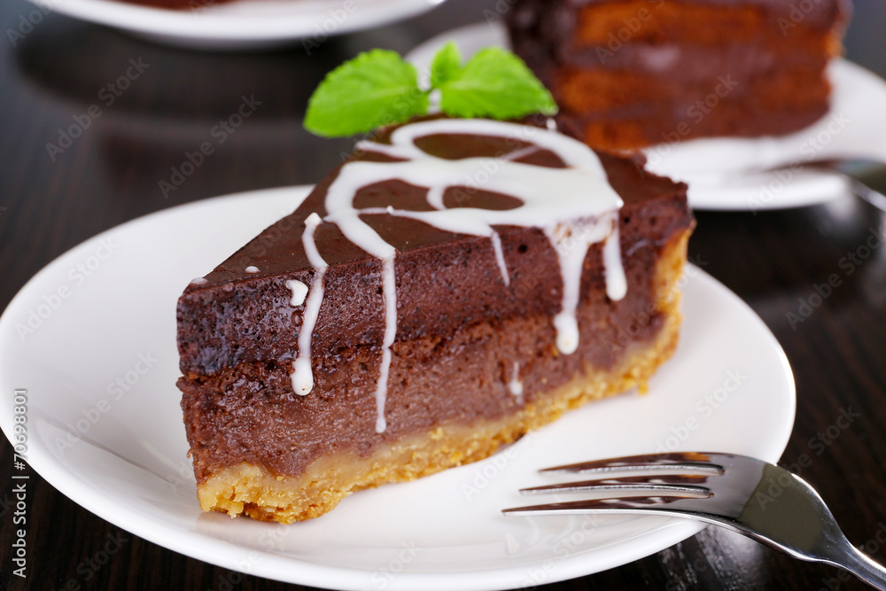 Pieces of chocolate cakes on plates on wooden table closeup