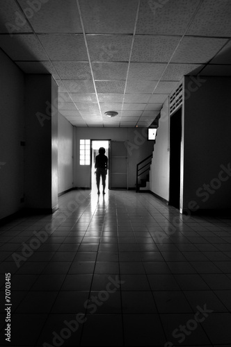Person s silhouette in doorway of dark empty room