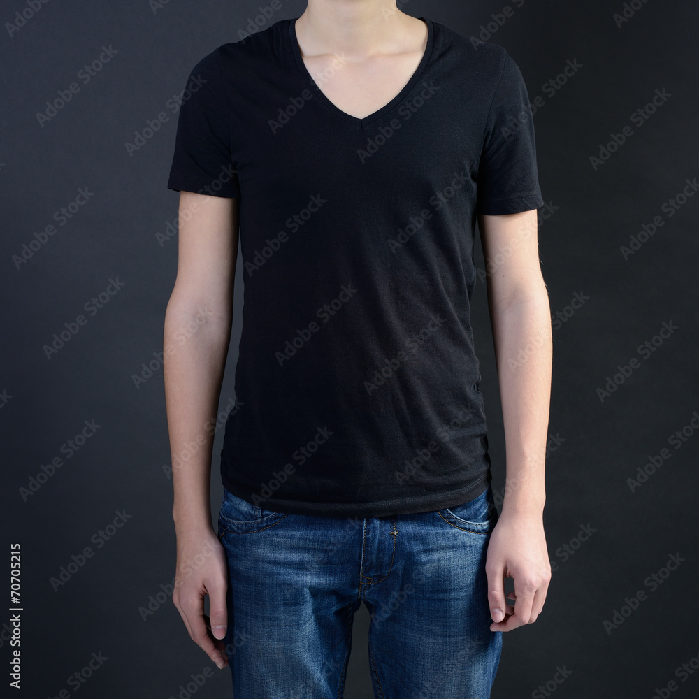 Obraz premium Young man in blank black t-shirt over dark background, teen boy