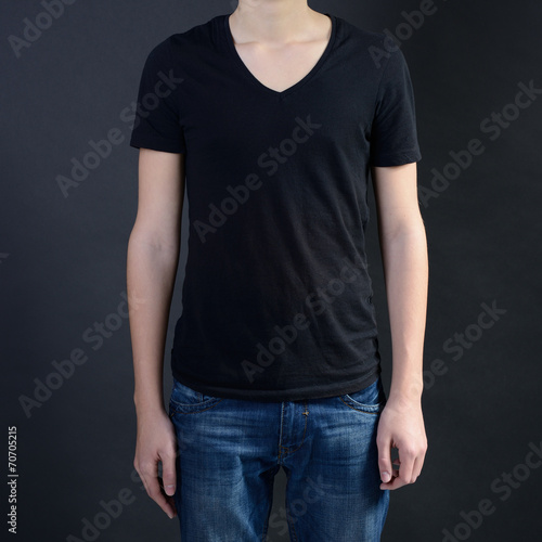 Young man in blank black t-shirt over dark background, teen boy