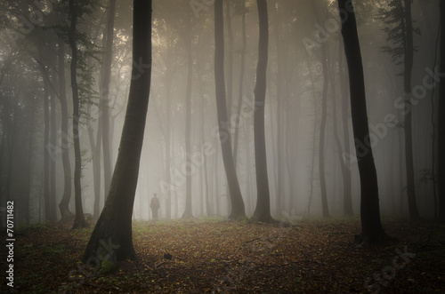 man lost in dreamy forest with black trees photo