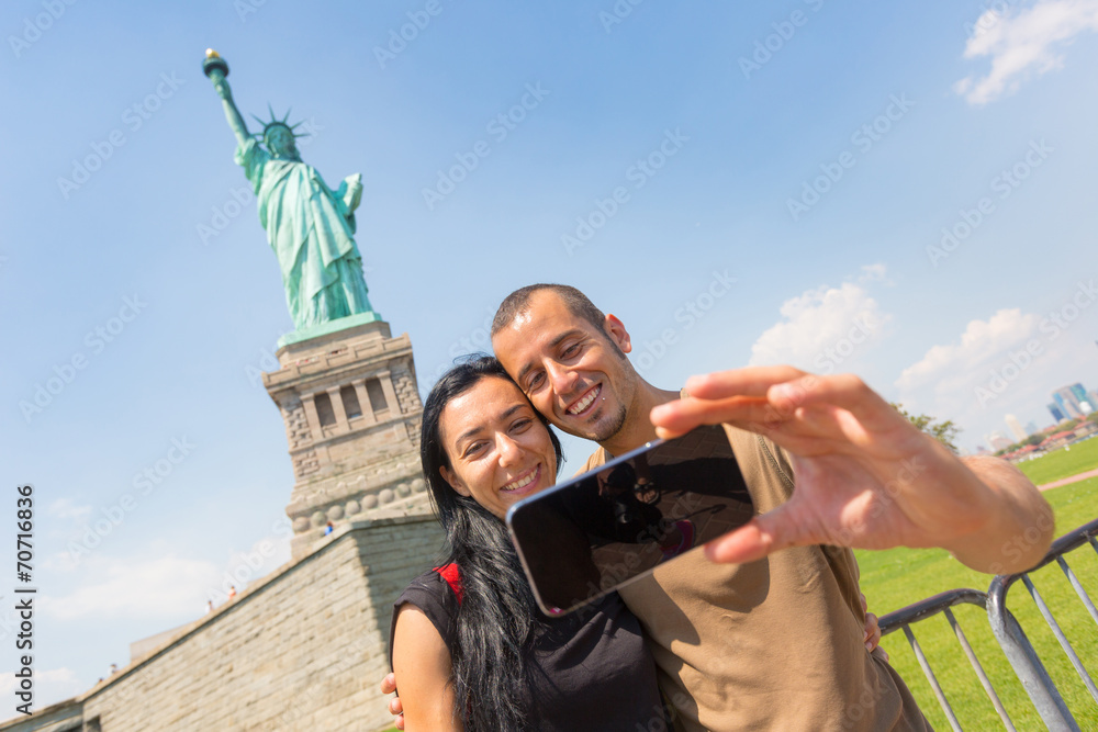Obraz premium Couple Taking a Selfie with Statue of Liberty on Background