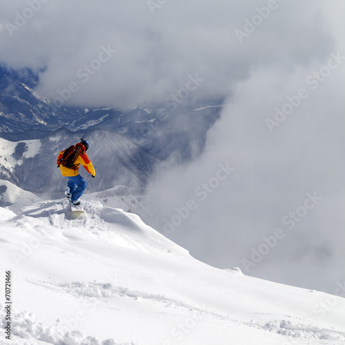 Snowboarder on off-piste slope an mountains in mist