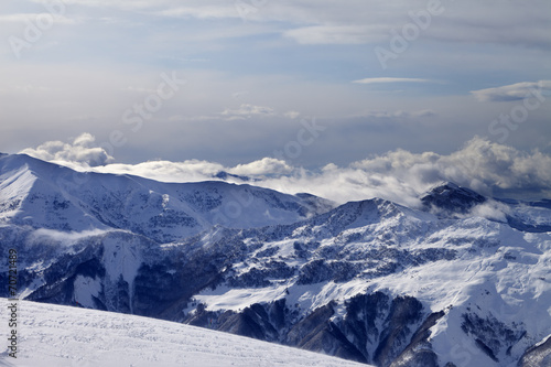 Winter mountains in clouds and ski slope © BSANI