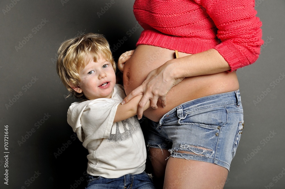 Small child holds a stomach of pregnant mother Small child holds a stomach of pregnant mother