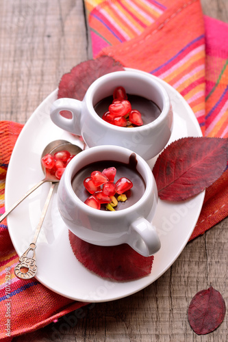 chocolate cream with pomegranate seeds on a wooden table