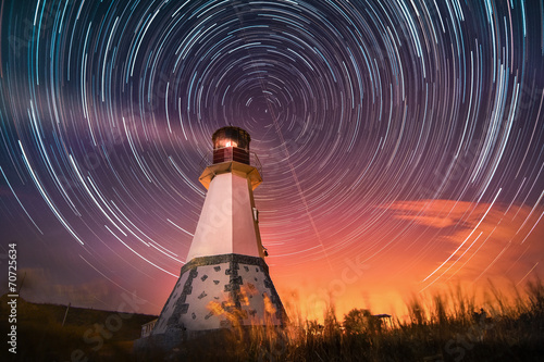 lighthouse with night sky at background stars trails