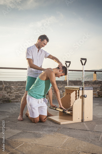 Pilates personal trainer doing class on a machine outdoors