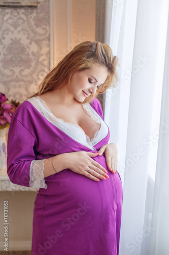 Beautiful pregnant girl in a bathrobe at the window