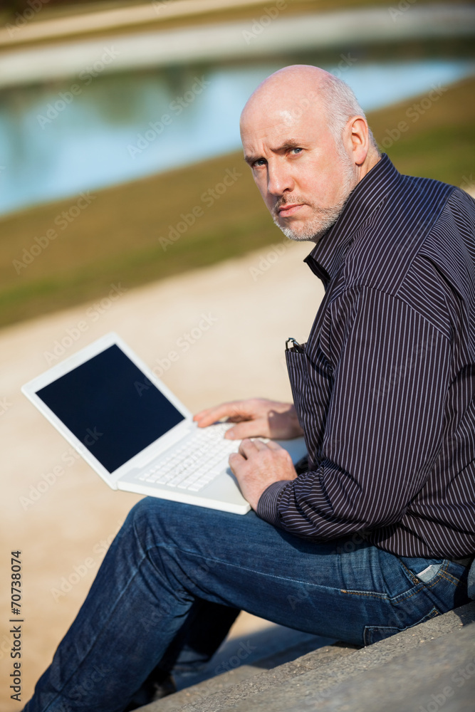 Man sitting on a bench using a laptop Man sitting on a bench using a laptop