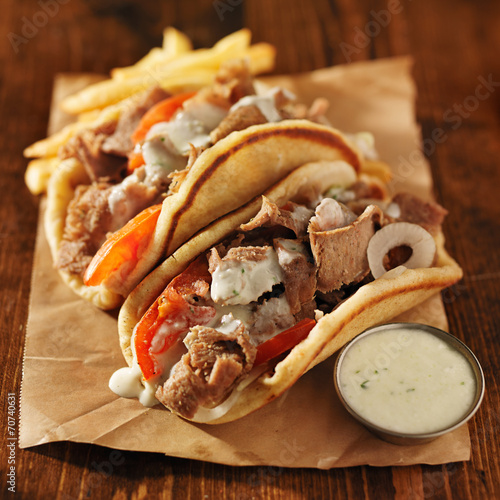 greek gyros with tzatkiki sauce and fries on parchment