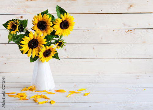 Fototapeta Naklejka Na Ścianę i Meble -  A bouquet of autumn sunflowers in a vase on a wooden table.