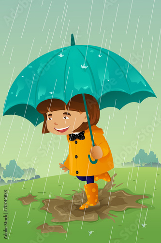 Girl with umbrella and raincoat playing in the mud