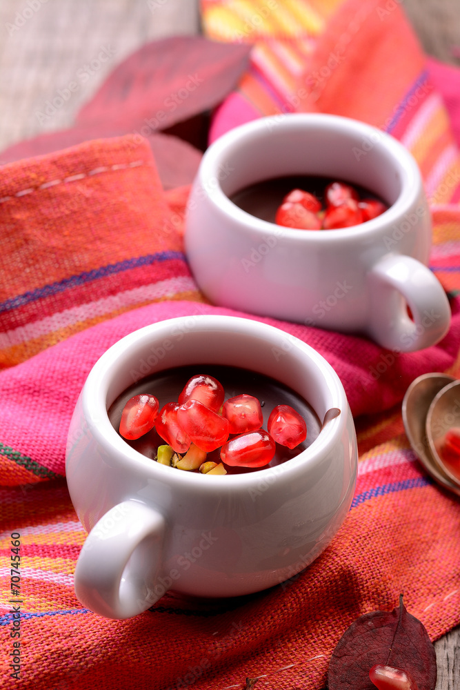 chocolate cream with pomegranate seeds on a wooden table chocolate cream with pomegranate seeds on a wooden table
