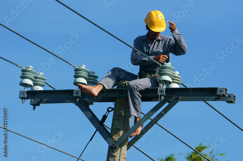 Asian electrician climb high, work on electric pole