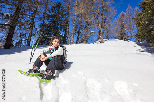 Ragazza seduta su neve con ciaspole