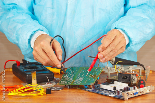Master checks electronic hardware with a multimeter