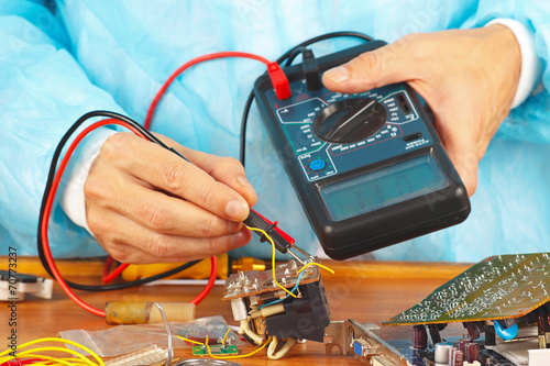 Serviceman checks electronic hardware with a multimeter