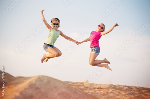 two girls jumping over blue sky