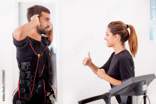 Foto Female coach giving man ems electro muscular stimulation exerci