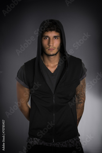 Handsome young man in dark hoodie on black
