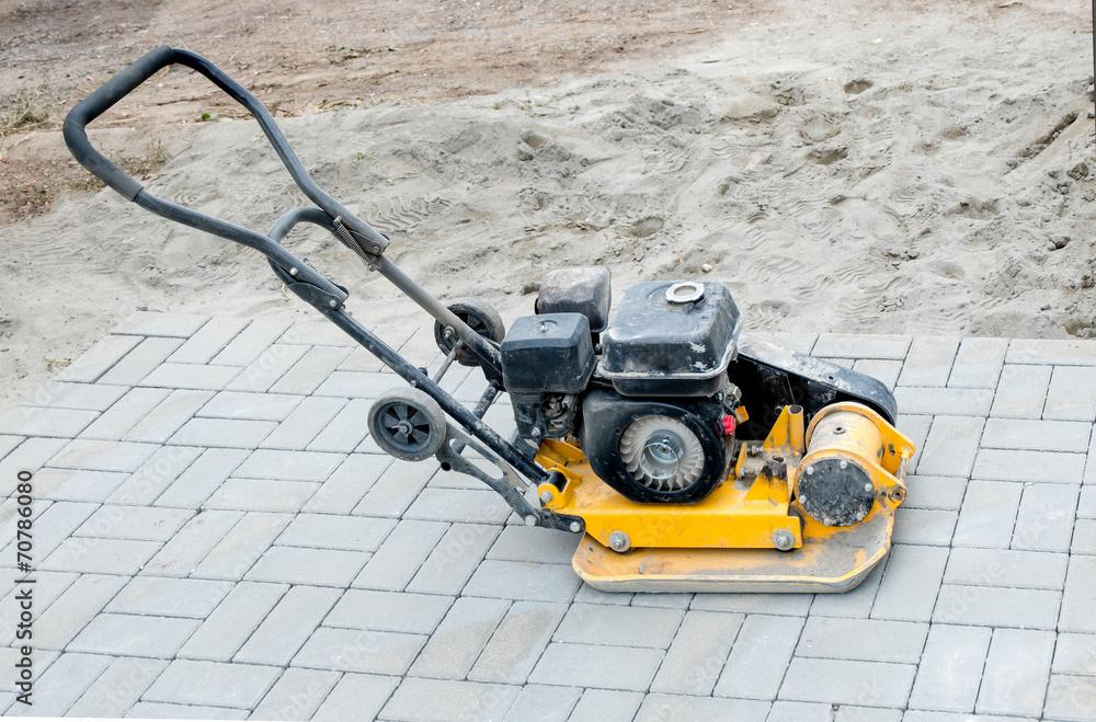 Fototapeta premium Small yellow compactor standing on new gray pavement