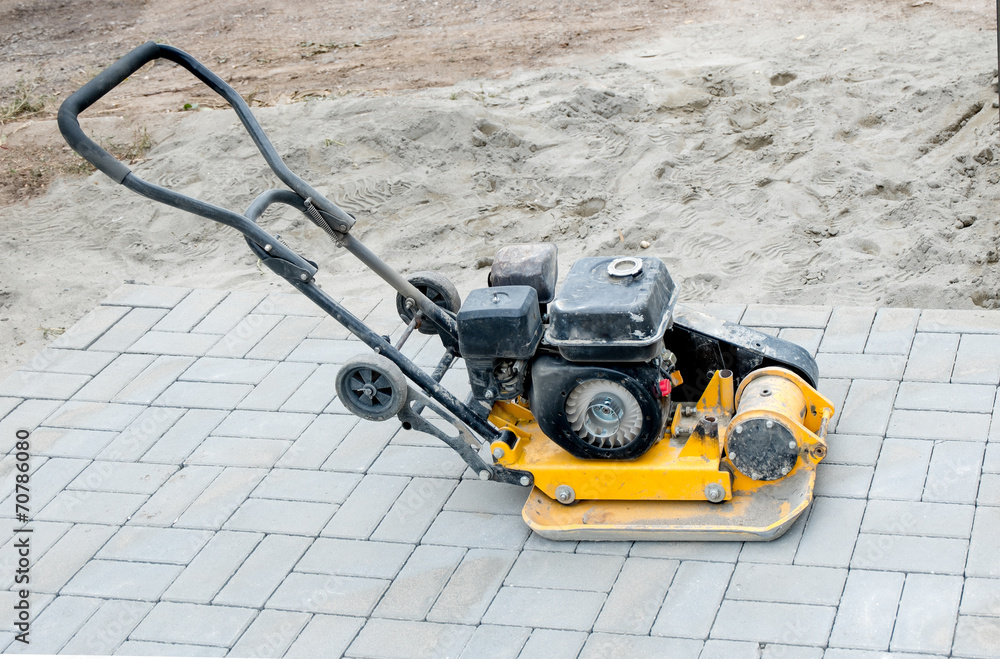 Small yellow compactor standing on new gray  pavement