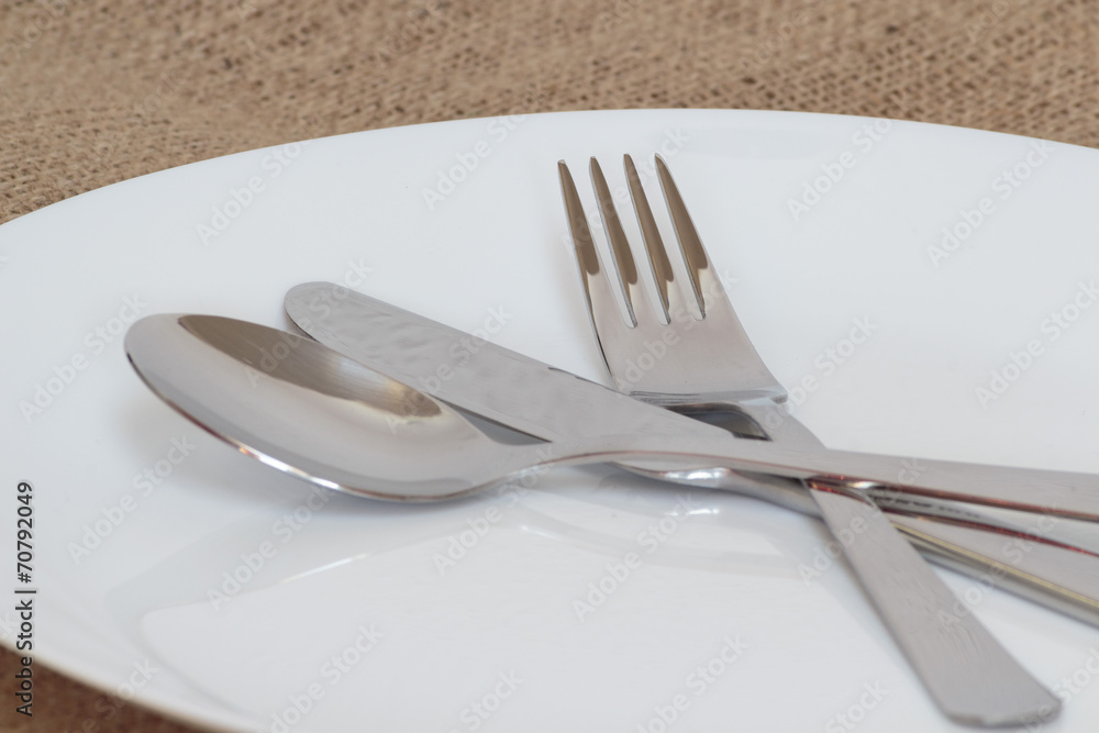 Fork, knife and spoon on white glass plate Fork, knife and spoon on white glass plate