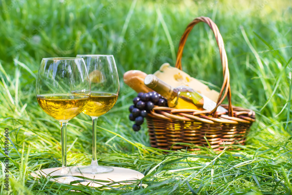 Picnic set with basket and two glasses of white wine Picnic set with basket and two glasses of white wine