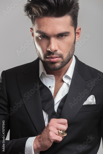 elegant young man ajusting his tuxedo photo