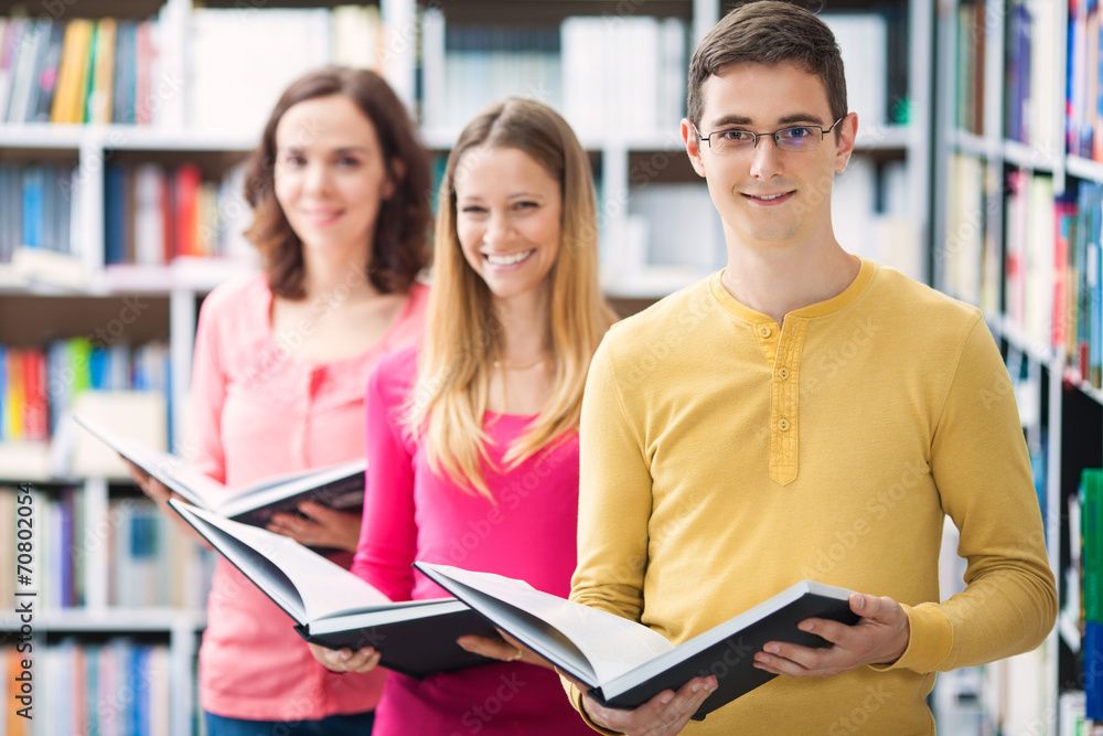 Group of three people holding books in library Group of three people holding books in library