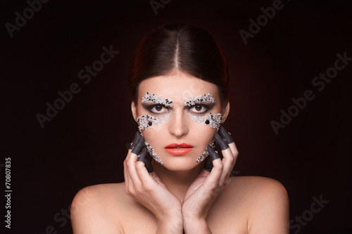 Beautiful woman with crystals makeup keep her hands near face