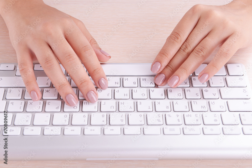 Female hands typing on keyboard on light background Female hands typing on keyboard on light background