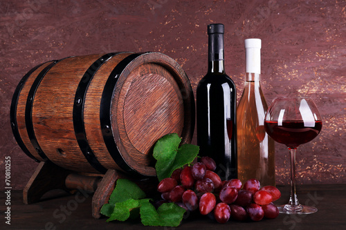 Wine in bottles and in goblet, grapes and wooden barrel