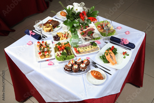 Laid table with a variety of dishes, fish, pastries, pickles
