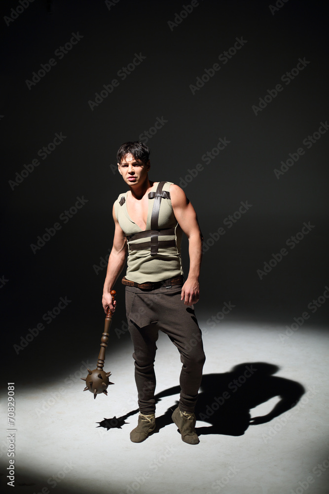Handsome young man standing with a mace in hand Handsome young man standing with a mace in hand