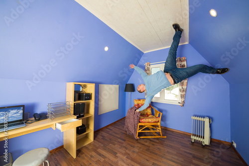 Foto Man in jeans running on ceiling upside down at inverted house