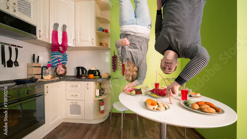 Family upside down in kitchen with table and dishes