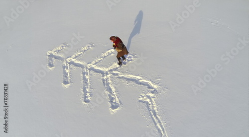 Girl in a fur coat outdoor drawing arrow on snow photo