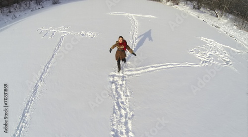 Aerial view to girl in coat and shawl outdoor running in snow photo