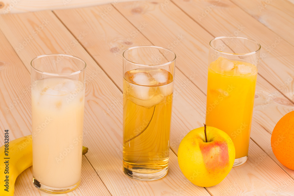 Three juices orange apple banana on wood. Three juices orange apple banana on wood.
