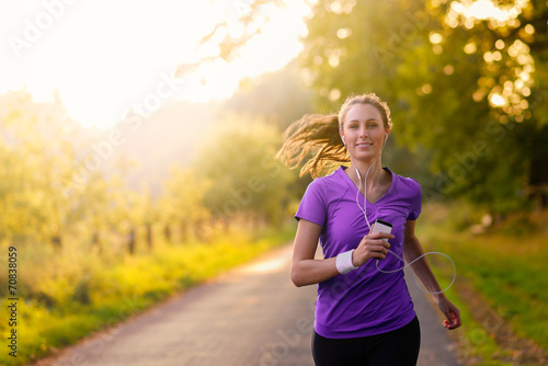 Vászonkép Sportliche Frau hört Musik beim Jogging