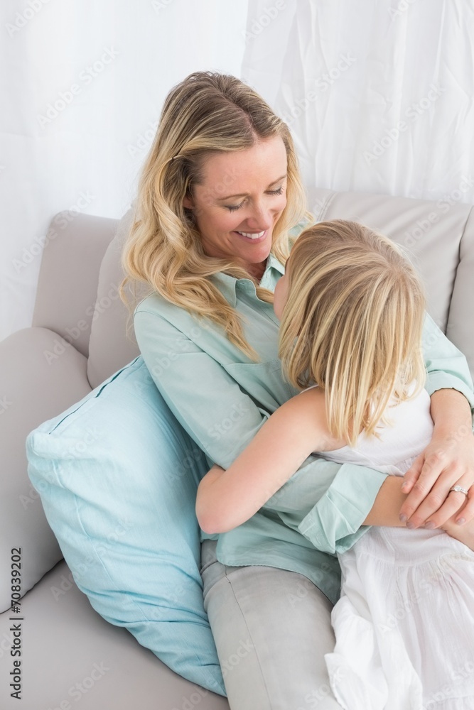 Mother sitting on the couch with her daughter smiling at camera