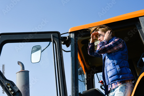 cheerful young woman farmer driving tractor in the fields