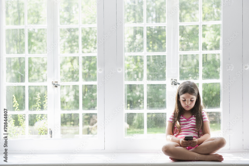 Girl with smart phone sitting at window Girl with smart phone sitting at window