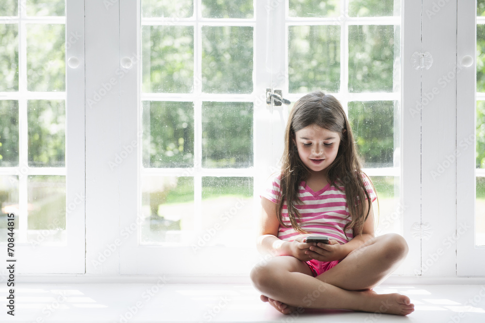 Girl with smart phone sitting at window Girl with smart phone sitting at window