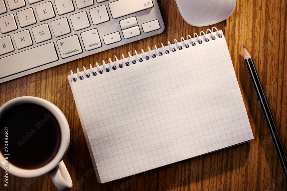 Open notebook with coffee alongside a keyboard Open notebook with coffee alongside a keyboard