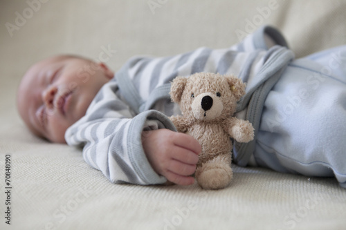Portrait of sleeping baby boy lying on blanket with teddy